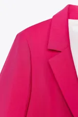 Blazer fucsia de cuello solapa y manga larga con hombreras. Detalle de tejido efecto arrugado. Bolsillos delanteros de vivo. Cierre frontal con un botón.