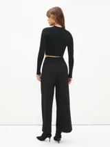 Pantalón negro de corte palazzo con cintura alta y botón.