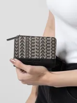 Monedero Marc Jacobs modelo The Monogram Travel Pouch, con cierre de cremallera y estampado del logo de la marca en tonos beige y negro.