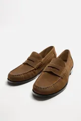 Mocasín color marrón de cuero con acabado serraje, antifaz, horma redonda y suela con ligero tacón.