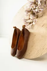 Zapato tipo ballerina color beige con correa al tobillo desmontable.