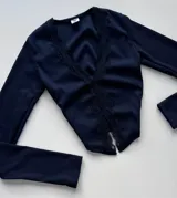 Remera corta negra de punto canalé con escote en V y detalles de encaje.