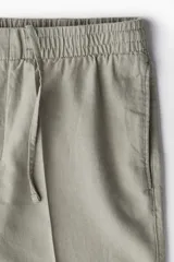 Short color gris claro confeccionado en mezcla de lino y algodón, corte regular, con cintura elástica, bolsillos laterales y trasero.