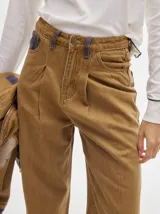 Pantalón de denim color marrón claro, de tiro alto, corte amplio y pinzas en la cintura.