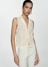 Blusa negra sin mangas con cuello camisero y cierre de lazos en la parte delantera.