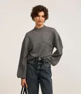 Suéter gris de punto, corte corto, con cuello alto y mangas largas abullonadas.