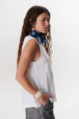 Top sin mangas color terracota con cuello redondo y bolsillo frontal. Presenta costuras a contratono en blanco que definen los bordes y el bolsillo.