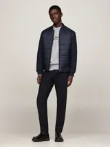 Campera bomber azul marino con mangas largas, cuello, puños y bajo acanalados. Presenta cierre frontal con cremallera, dos bolsillos laterales y logo de Tommy Hilfiger bordado en el pecho.