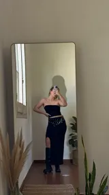 Conjunto negro de top bandeau y falda larga con tajo lateral, confeccionado en jersey de lycra. Incluye cinturón negro con apliques metálicos.