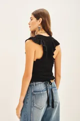 Musculosa negra tejida en hilo de algodón con punto desagujado, calce al cuerpo y volados en las sisas.