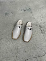 Sueco de cuero negro con detalle de apliques metálicos triangulares plateados.