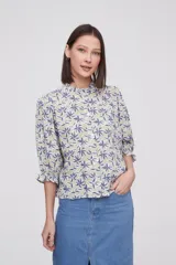 Blusa estampada con flores azules y hojas verdes, cuello mao con volados, mangas 3/4 con volados en los puños y cierre frontal con botones.
