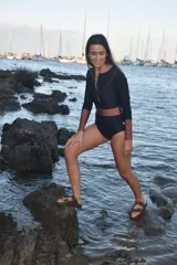 Traje de baño enterizo negro con mangas largas color cobre y cinturón ancho color cobre.