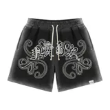 Bermuda de felpa negra con efecto lavado (washed) que aclara hacia los laterales. Presenta un gran estampado serigrafiado en blanco con motivos florales y caracteres orientales estilizados. Posee cordón de ajuste en la cintura y remaches metálicos cromados en los laterales.