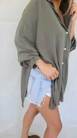 Camisa negra de corte amplio, con mangas largas y puños abotonados.