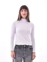 Polera blanca de cuello alto y mangas largas, con terminaciones onduladas en ruedo y puños.