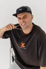 Remera color beige con estampado de una pieza de ajedrez en color naranja en la espalda.