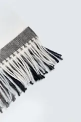 Bufanda rectangular con diseño a cuadros en tonos gris, blanco y marrón, con flecos en los extremos.
