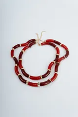 Collar corto de cuentas tubulares rojas y borgoña alternadas con detalles dorados.