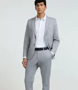 Pantalón de vestir gris claro con textura, de corte recto, con bolsillos laterales y traseros. Se ajusta a la cintura con cinturón de cuero negro.