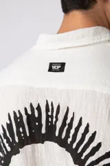 Camisa blanca de lino con cuello clásico, manga corta y cierre frontal con botones.