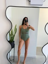 Traje de baño entero verde con breteles finos, escote redondo y detalle de transparencia en la cintura.