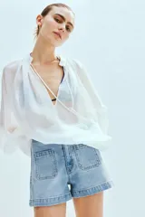 Short de denim celeste de tiro alto, con bolsillos frontales tipo parche y bolsillos traseros. Cierre frontal con botón metálico.
