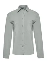 Camisa manga larga color gris claro, con cuello camisero, cierre frontal con botones y dos bolsillos con solapa en el pecho. Confeccionada en algodón orgánico con tecnología UPF +50.