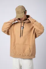 Buzo canguro color ocre con capucha y cordones negros, de corte oversize y confeccionado en tela de algodón friza con teñido artesanal y estampa circular en el pecho.