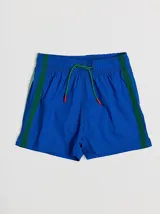 Short de baño azul con cintura elástica, rayas verdes en los laterales y bolsillo trasero con solapa roja y verde.