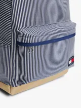 Mochila Tommy Jeans Essential con diseño a rayas verticales azules y blancas, base color beige, asa superior y correas acolchadas ajustables. Cuenta con compartimento principal con cierre de cremallera, bolsillo interior de malla y bolsillo exterior con cremallera.