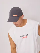 Gorra gris de poliéster y elastano con visera curva y logo de la marca Rusty en color naranja.