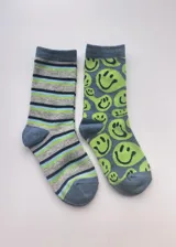 Pack de dos pares de medias de media caña. Un par a rayas horizontales en tonos gris, azul y verde. El otro par con estampado de caritas sonrientes en verde sobre fondo azul.