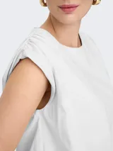 Musculosa blanca de algodón, corte amplio, sin mangas y cuello redondo.