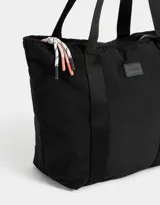 Bolso negro tipo shopper de tela deportiva con doble asa de hombro, cierre superior con tirador de cordón y goma, y etiqueta de goma con logo.