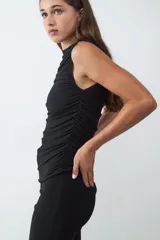 Top básico negro sin mangas con cuello redondo y diseño drapeado.