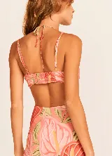 Vestido largo de tirantes finos con estampado de hojas en tonos coral, naranja, verde y amarillo. Presenta escote en V con detalle de nudo y aberturas en los laterales de la cintura.