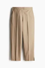 Pantalón cigarette tobillero color beige, con cintura estándar, cierre y pretina prolongada con corchete oculto. Piernas ajustadas con abertura corta en los bajos, bolsillos al bies y bolsillo de atrás decorativo. Pliegues adelante y atrás.