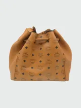 Cartera bombonera de cuero color camel con monograma estampado y tachas doradas.