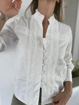 Camisa blanca de corte clásico con detalles de encaje en el frente y mangas largas con puños abotonados.