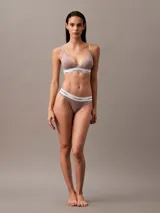 Conjunto de ropa interior Calvin Klein color topo, compuesto por un corpiño triangular con breteles finos y una colaless, ambos con banda elástica blanca con el logo de la marca.