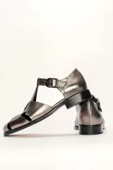 Sandalia roja de cuero vacuno con diseño de tiras entrecruzadas y hebilla lateral. Tiene suela de cuero artesanal y taco bajo.