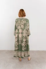 Vestido largo azul con estampado floral en tonos beige, confeccionado en viscosa. Presenta escote en V, botonadura completa en el frente y mangas largas con volados.