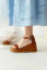 Sandalias de cuero color marrón con plataforma y taco de cuña. Tiras anchas con textura tipo cocodrilo y hebilla metálica plateada.