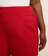 Bermuda roja de crepé con cierre delantero, bolsillos laterales con botones y pliegues.