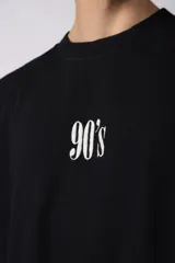 Remera color crema de corte oversize con la inscripción '90's' bordada en el frente y parche con imagen en la espalda.