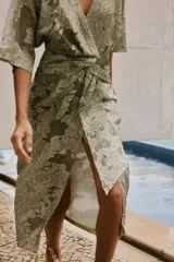 Vestido midi color verde oliva con estampado floral, escote en V, manga corta amplia y detalle drapeado en la cintura.