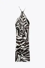 Vestido largo de viscosa con estampado animal en blanco y negro. Tiene cuello halter ajustable con lazos y bajo asimétrico.