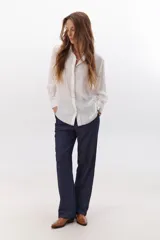 Camisa negra de manga larga con cuello clásico y cierre frontal con botones. Presenta costuras decorativas en color blanco.
