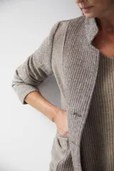 Chaqueta corta color marrón con cuello solapa y diseño con patchwork de telas. Manga larga con detalle de coderas aplicadas. Cierre frontal mediante botones y bolsillos ojal. Con forro.